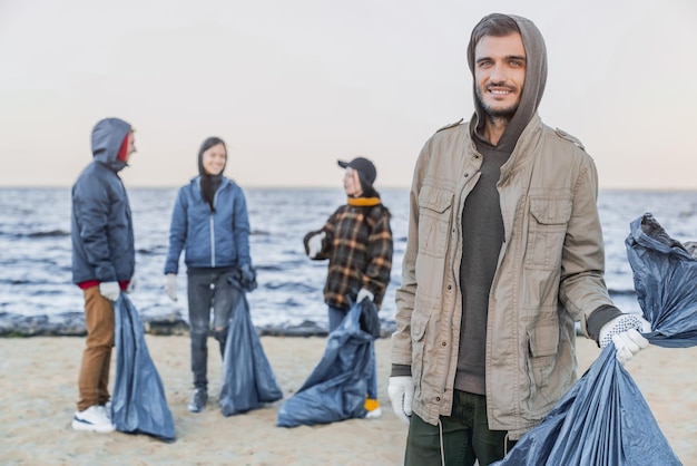 プラスチックのゴミを拾った後、カメラで笑っている若い混血男性ボランティアの肖像画