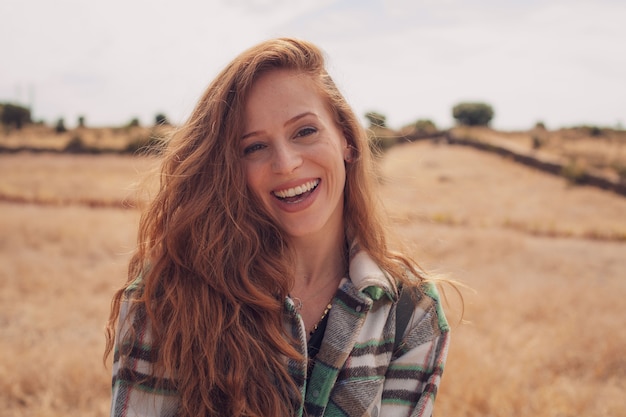 Foto ritratto di una giovane modella che sorride alla telecamera con un campo sullo sfondo