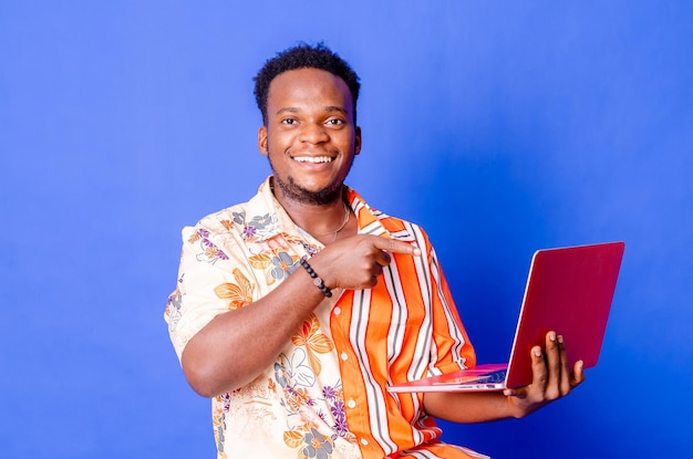 portrait of young modern businessman standing holding laptop and looking at camera with happy smile