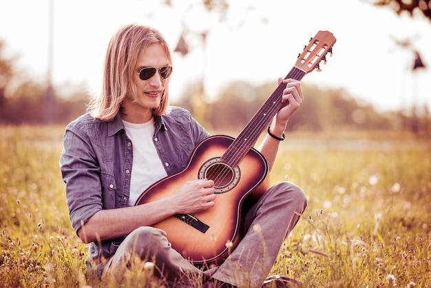 Portrait of young modern guy with acoustic guitar