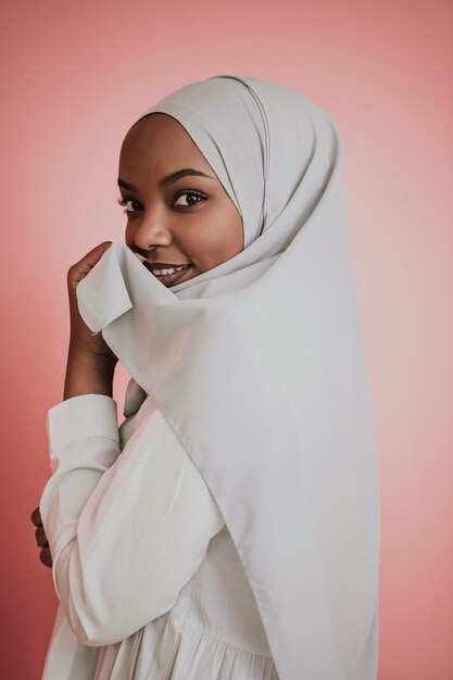 Portrait of young modern muslim afro beauty wearing traditional islamic clothes on plastic pink background. Selective focus. High quality photo