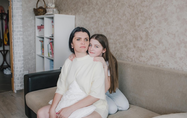 Portrait of a young mother and daughter hugging at home on the couch. happy family