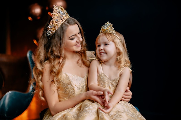 Portrait of young mother and little daughter in luxurious dresses
