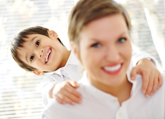 Portrait of young mother piggybacking her son indoor