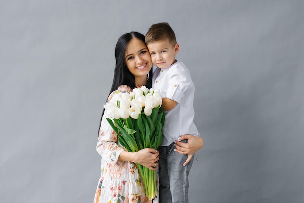 Photo portrait of a young mother with a bouquet of white tulips and a young son having fun