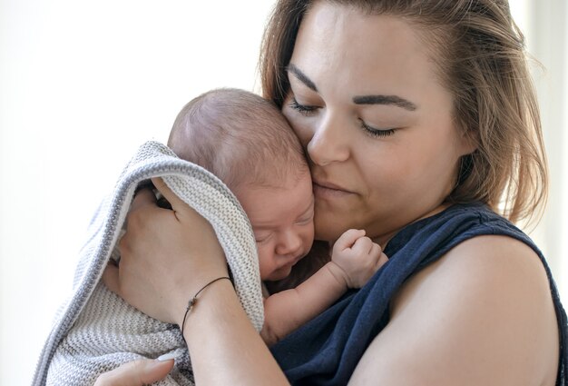 Portrait of a young mother with a newborn baby in her arms.