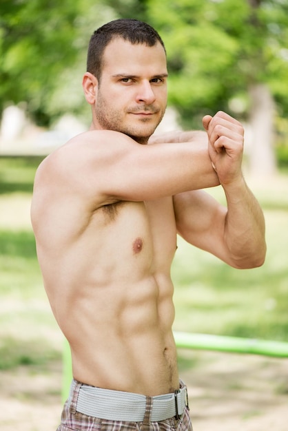 Portrait on young muscle Man doing exercise in the park.Looking at camera.