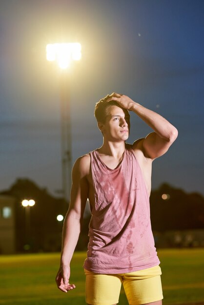 Portrait of a young muscular sweat sportsman posing on stadium