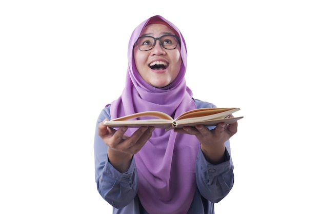 Portrait of young muslim businesswoman wearing hijab reading book with surprised expression