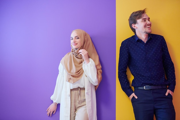 現代のイスラム教のファッションとラマダン カリームの概念を表すカラフルな背景に分離されたヒジャーブとファッショナブルなドレスで若いイスラム教徒のカップルの女性の肖像画