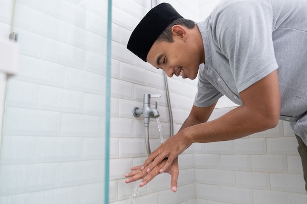 Portrait of young Muslim man perform ablution (wudhu) before prayer at home. clean his hand