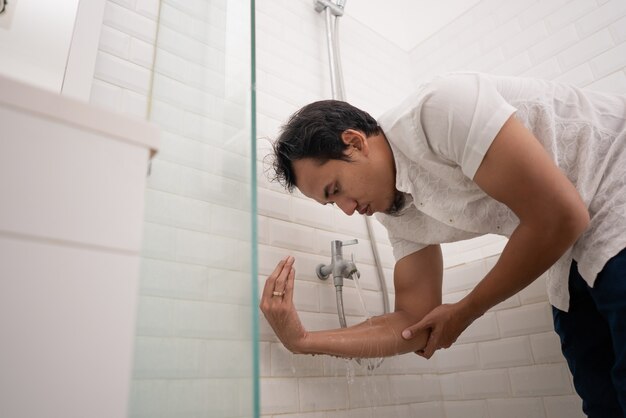 Portrait of young Muslim man perform ablution (wudhu) before prayer at home