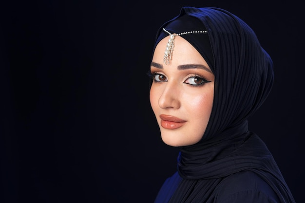 Портрет молодой мусульманской женщины в хиджабе на черном фоне