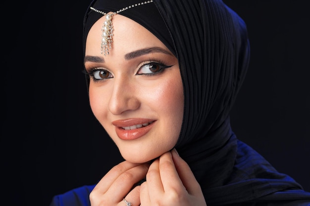 Портрет молодой мусульманской женщины в хиджабе на черном фоне