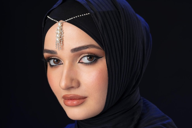 Portrait of a young muslim woman in hijab on black background