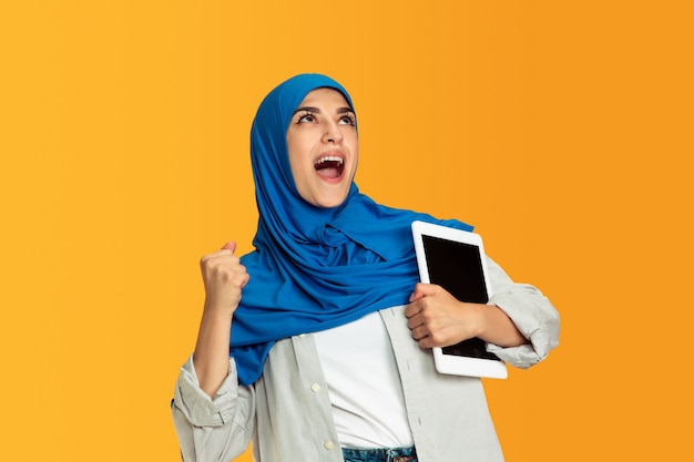 Portrait of young muslim woman isolated on yellow studio background