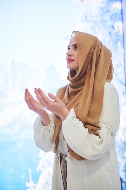 Портрет молодой мусульманки, молящейся или делающей дуа Богу. Девушка с современной и модной одеждой на фоне зимней концепции.