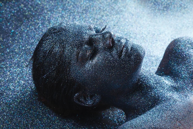 Portrait of young  mystical fantasy woman from another world covered with tinsels lying on her back on a floor. Girl from a dream