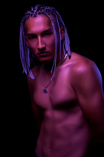 Portrait of a young naked african man at studio High Fashion male model in colorful neon bright lights posing on black background Art design concept selective focus