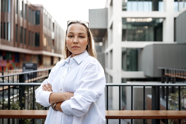 Portrait of young office woman standing on balcony enjoying city view