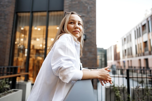 Portrait of young office woman standing on balcony enjoying city view