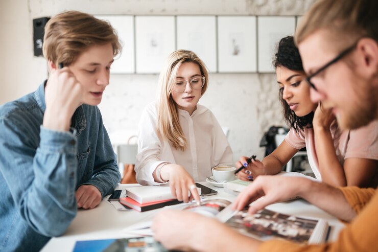 Portrait of young people thoughtfully discussing journals in office.