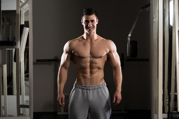 Portrait of a young physically fit man showing his well trained body muscular athletic bodybuilder fitness model posing after exercises