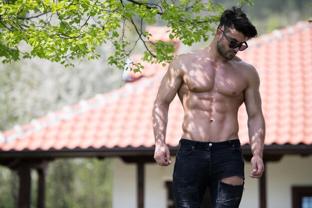 Портрет молодого физически здорового мужчины, демонстрирующего свое хорошо тренированное тело в черных джинсах