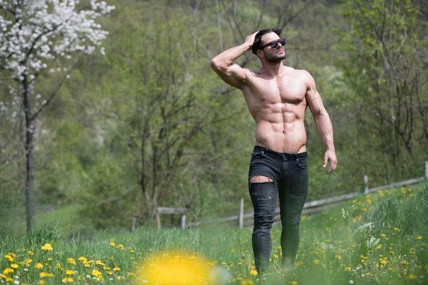 Portrait of a Young Physically Fit Man Showing His Well Trained Body While Wearing Black Jeans  Muscular Athletic Bodybuilder Fitness Model Posing After Exercises Outdoors  a Place for Your Text