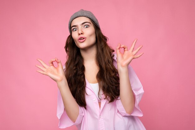 Portrait of young positive surprised beautiful curly brunette woman with sincere emotions wearing