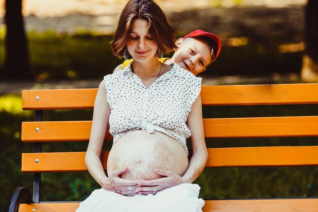 Portrait of young pregnant woman playing outdoor peekaboo with her son