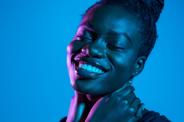 Portrait of young pretty african woman possing in neon light space. Skin care concept.