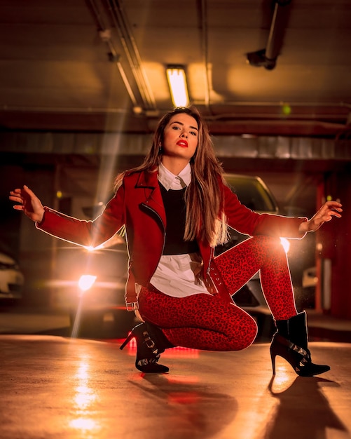 Portrait of a young pretty blond Caucasian crouching in a red suit