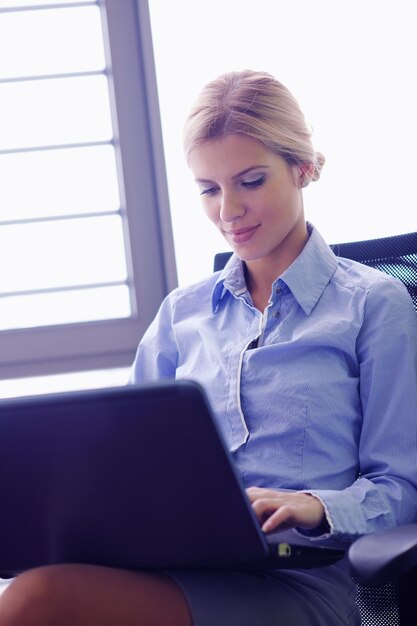 portrait of Young pretty business woman work on  notebook computer  in the bright modern office indoors