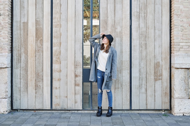 A Portrait young pretty Caucasian girl, dressed in a gray jacket, a white sweater and a hat.