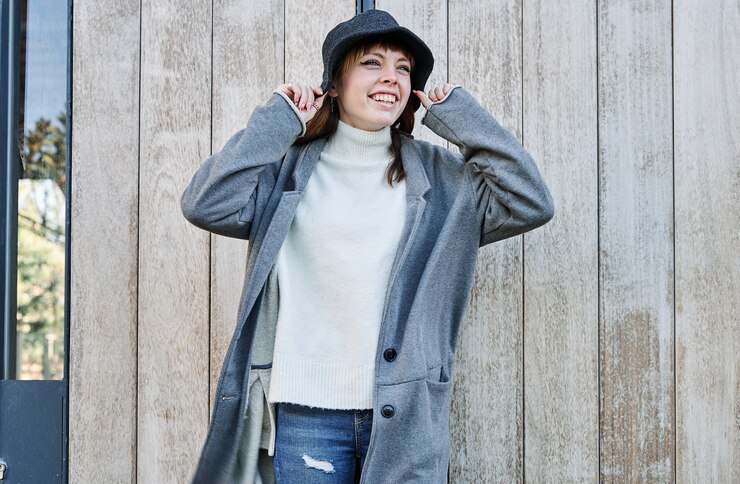 Photo 灰色のジャケット、白いセーター、帽子を着た肖像画の若いかわいい白人の女の子。