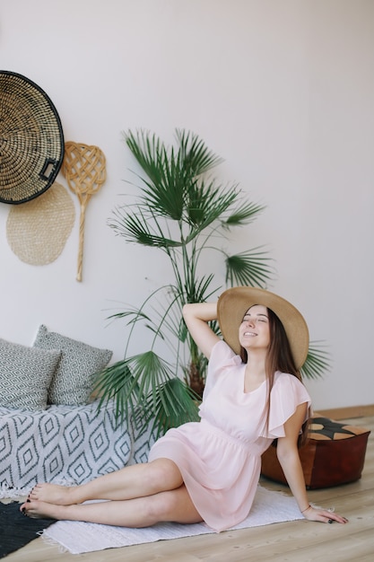 Portrait of a young pretty happy woman in a pink dress and a straw hat with rustic background