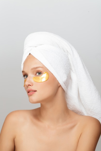 Portrait of young pretty lady with white towel on head with yellow patches under eyes