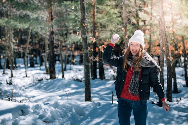 肖像画の若いきれいな女性を楽しんで、冬に雪で遊ぶ