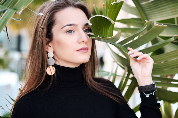 Portrait of a young pretty woman posing next to the tree