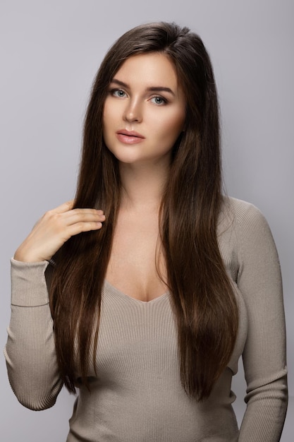 Portrait of young pretty woman with a beautiful long hair on gray background