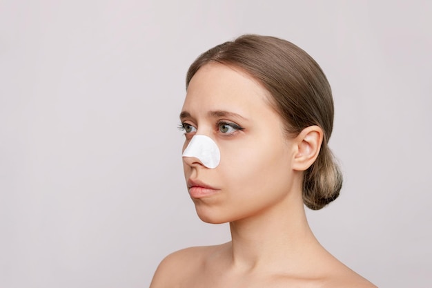 Portrait of a young pretty woman with cleaning nose strips from blackheads black dots on her skin