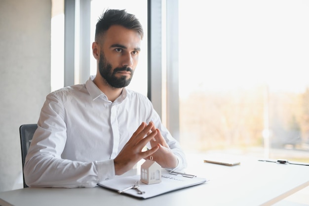 Portrait of a young realtor in the office at the table real\
estate sales concept