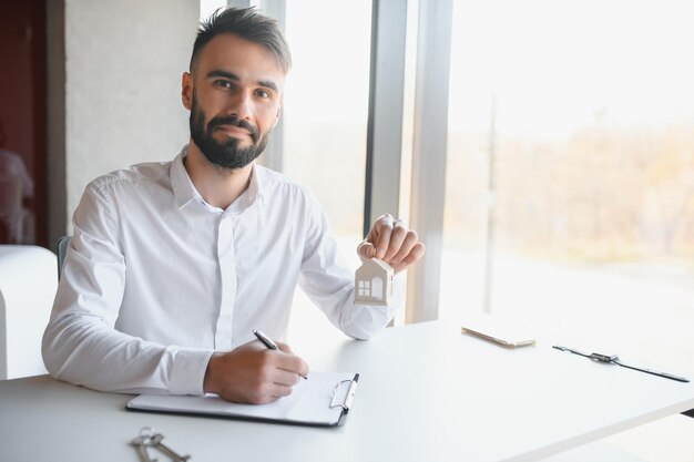 Portrait of a young realtor in the office at the table real\
estate sales concept