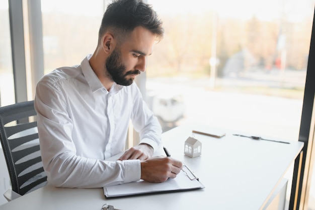 Portrait of a young realtor in the office at the table Real estate sales concept