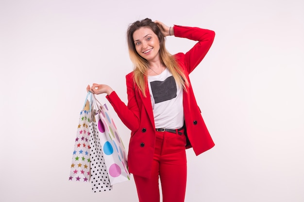 Portrait of young red-haired freckled woman with shopping bags on white background.