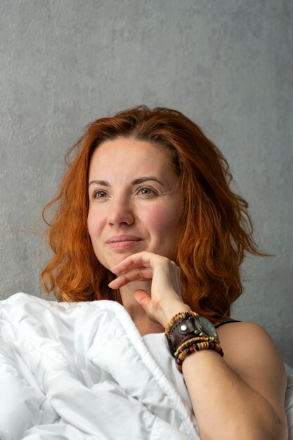 Photo portrait of young red-haired girl in the morning in bed. healthy face of beautiful awakened woman. vertical frame.