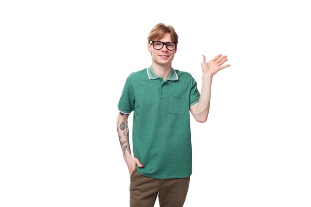 Портрет молодого рыжеволосого парня в зеленой футболке, улыбающегося милым на белом фоне с копией