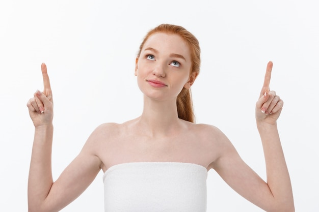 Portrait of young redhead female with perfect freckled skin showing something interesting at copy space wall for your advertising content.