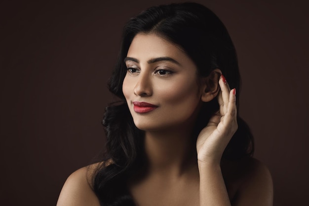 Портрет молодой и богатой индийской женщины с красивым макияжем и прической на коричневом фоне